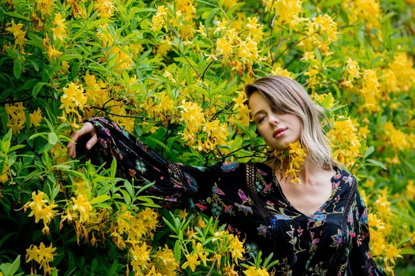 Donna di stile vicino a fiori gialli in un grarden in tempo di primavera — Foto Stock