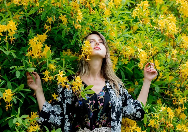 Donna di stile vicino a fiori gialli in un grarden in tempo di primavera — Foto Stock