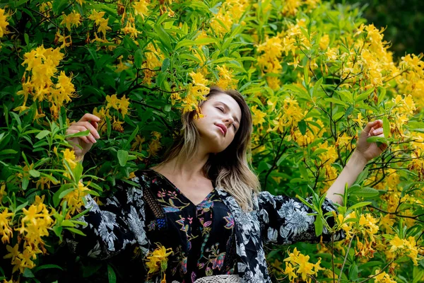 Donna di stile vicino a fiori gialli in un grarden in tempo di primavera — Foto Stock