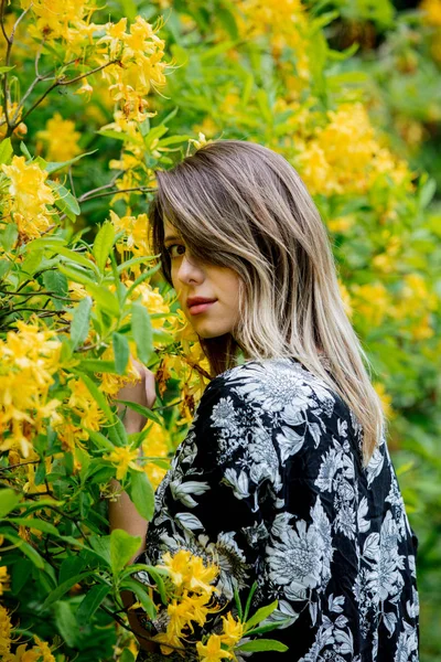 Žena ve stylu v jarním čase v blízkosti žlutých květin — Stock fotografie