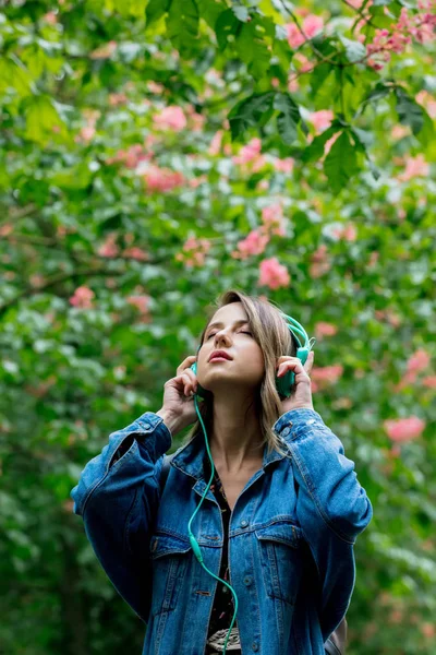 Vrouw met een koptelefoon bij bloesem bomen op de achtergrond in het voorjaar — Stockfoto
