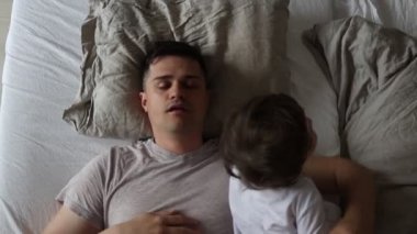 genç baba bir bebek çocuk ile bir yatakta yatan görüntüleri