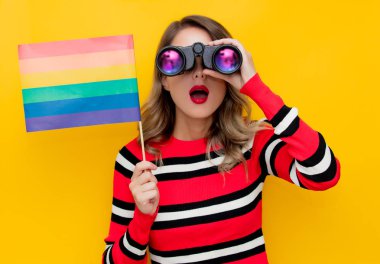 Dürbün ve Lgbt bayraklı kırmızı çizgili süveter giyen genç bir kadın. 