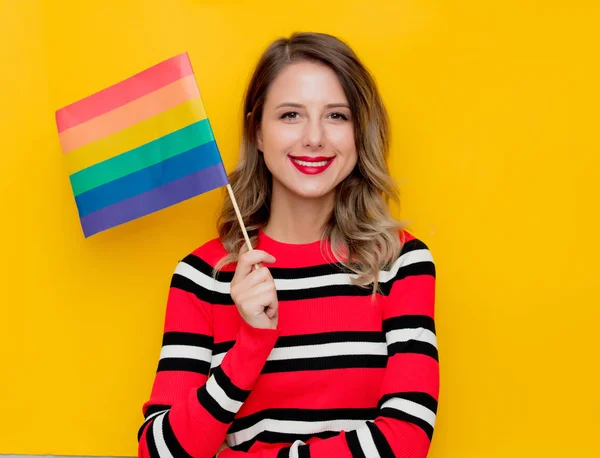Молода жінка в червоному смугастому светрі з прапором ЛГБТ — стокове фото