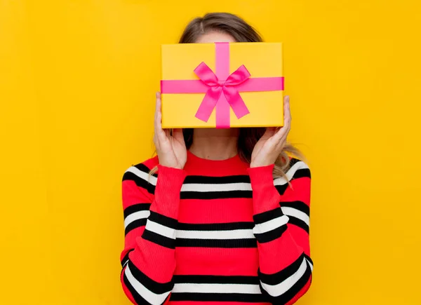 Девушка в красно-полосатом свитере с подарочной коробкой — стоковое фото