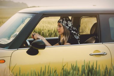 Kırsal bir yolda araba süren genç bir kadın.
