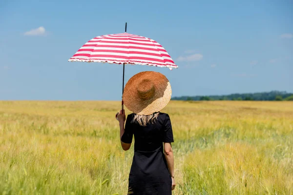 Vrouw in zwarte jurk en muts met rode paraplu verblijf in tarwe fi — Stockfoto