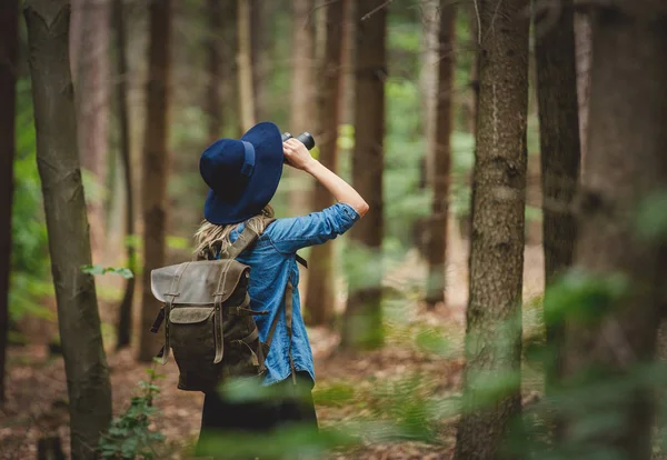 Ung kvinna med kikare och ryggsäck i en skog — Stockfoto