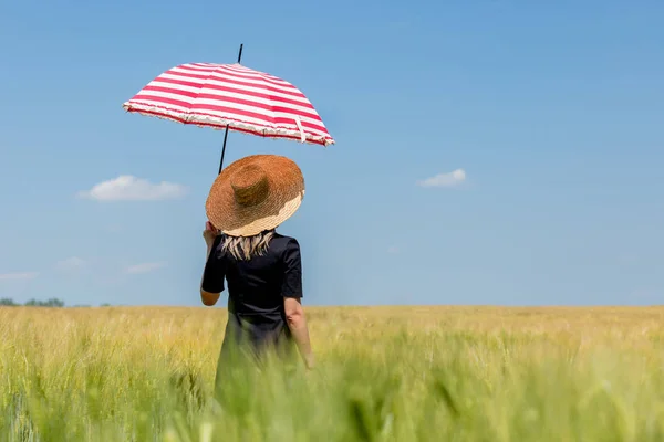 Mujer en vestido negro y sombrero con paraguas rojo estancia en fi trigo — Foto de Stock