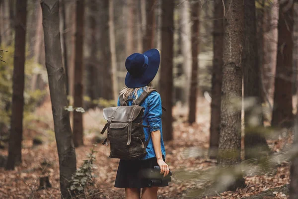 Ung kvinna med kikare och ryggsäck i en skog — Stockfoto