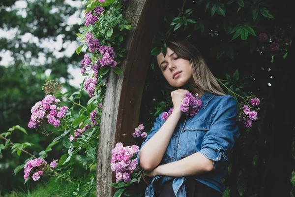 Giovane donna vicino a cespuglio di fiori viola in un giardino — Foto Stock