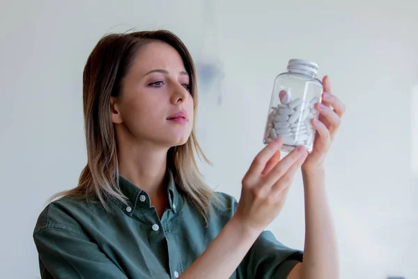Mujer sosteniendo un frasco transparente con pastillas blancas —  Fotos de Stock