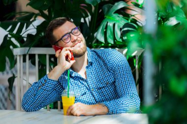 bir kafede cep telefonu kullanan genç adam