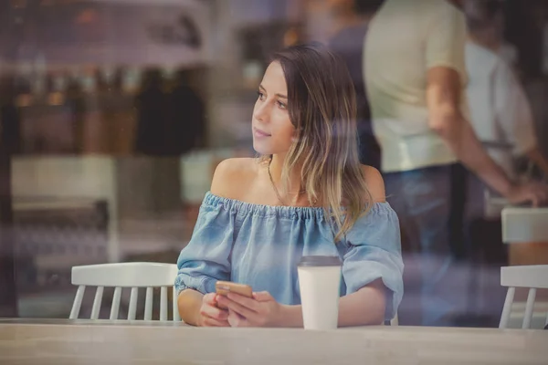 カフェでコーヒーを飲み、携帯電話を使う若い女性w — ストック写真