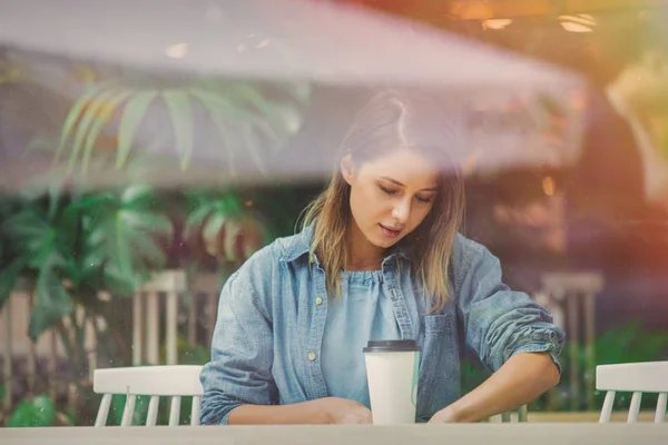 Mujer joven en un café y beber café mientras está sentado junto a la w —  Fotos de Stock