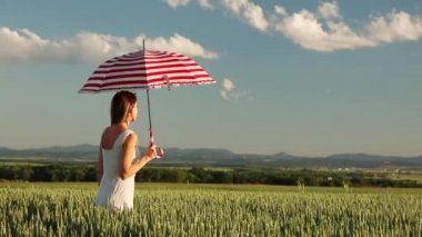 yeşil buğday tarlasında şemsiyeli genç kız