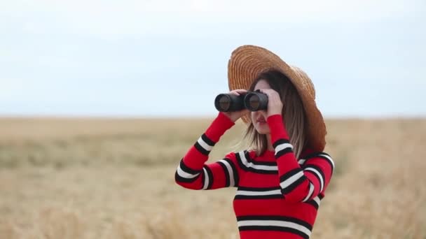 小麦畑に双眼鏡を持つ赤いセーターを着た若い女性 — ストック動画