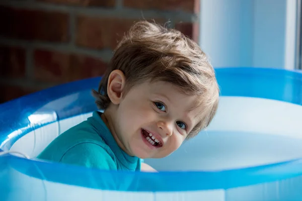 Pequeño niño se juega en una piscina inflable — Foto de Stock