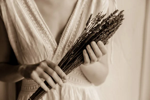 Donna in abito bianco che tiene la lavanda vicino alla finestra — Foto Stock