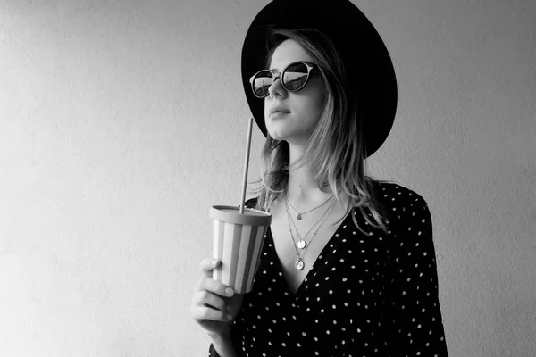 Jovem mulher de chapéu e óculos de sol com uma bebida . — Fotografia de Stock