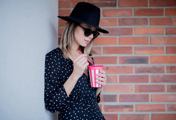 Vrouw in hoed en zonnebril met een drankje — Stockfoto