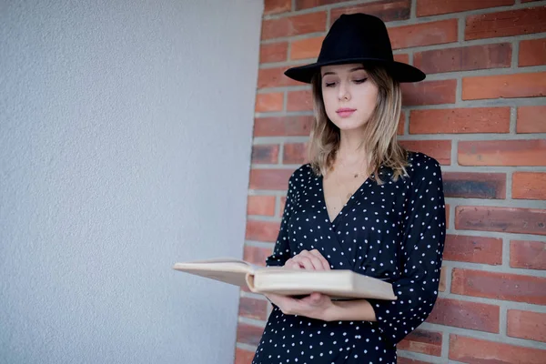 Femme en chapeau avec livre sur fond de mur de briques — Photo