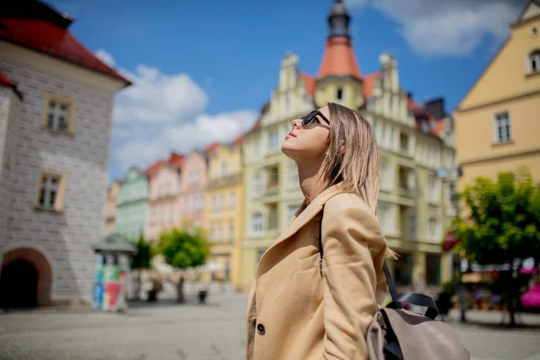 Woman in sunglasses and backpack in aged city center square. Poland — Stock Photo, Image