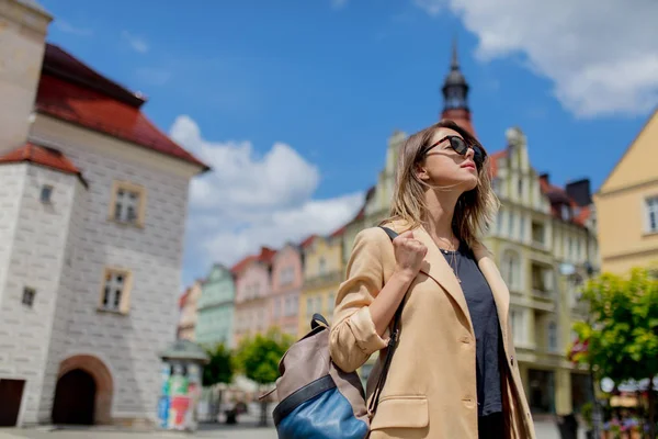 Mulher de óculos de sol e mochila na praça do centro da cidade envelhecida. Polónia — Fotografia de Stock