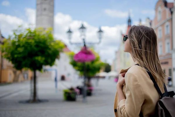 Mulher de óculos de sol e mochila na praça do centro da cidade envelhecida. Polónia — Fotografia de Stock