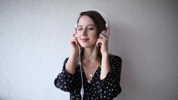 Mujer con auriculares y gafas de sol sobre fondo de pared de ladrillo — Vídeos de Stock