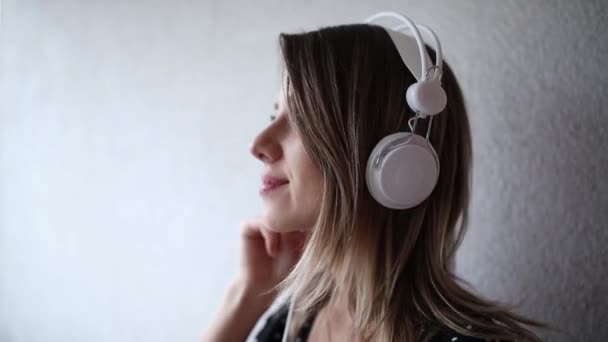 Vrouw met koptelefoon en zonnebril op bakstenen muur achtergrond — Stockvideo