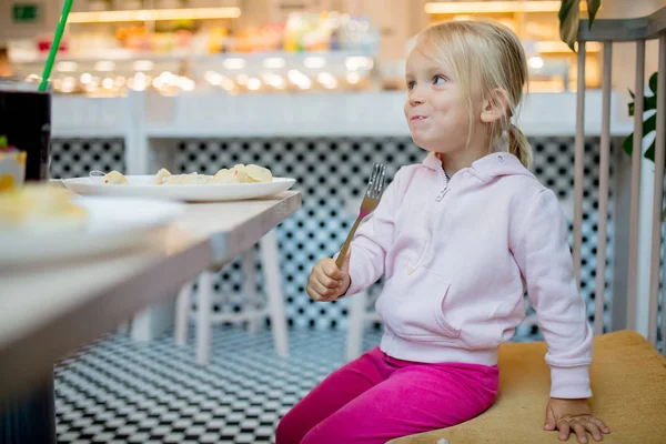 Маленькая девочка ест пельмени в кафе — стоковое фото