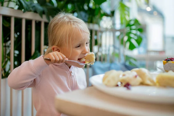 Piccola ragazza mangiare gnocco in caffè — Foto Stock