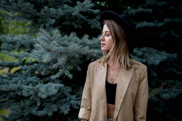 风格妇女帽子和夹克附近的松树 — 图库照片