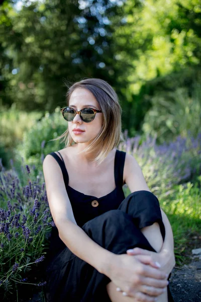 Frau sitzt neben Lavendelblüten in einem Garten — Stockfoto
