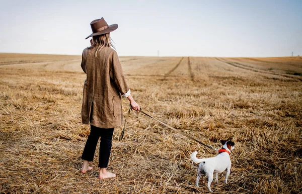 Γυναίκα με καπέλο με σκύλο στο χωράφι — Φωτογραφία Αρχείου