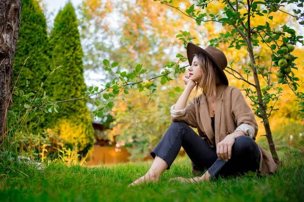 Женщина отдохнуть в саду рядом с молодой яблоней — стоковое фото