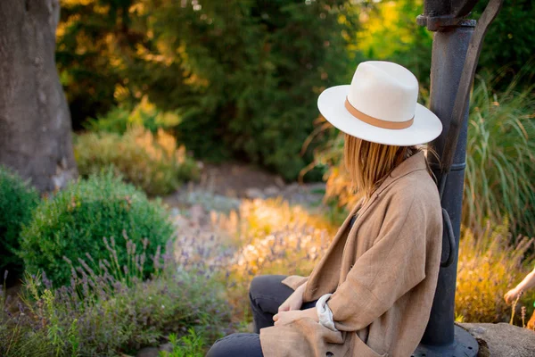 Vrouw in hoed zittend in de buurt van lavendel bloemen — Stockfoto