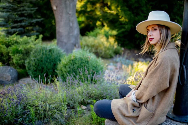 Woman in hat sitting near Lavender flowers — Stock Photo, Image