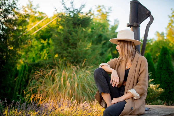 Femme en chapeau assise près de fleurs de lavande — Photo