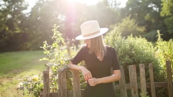 Woman in hat in a summertime countryside garden — Stock Video