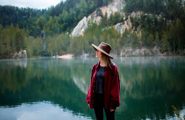 Frau mit Hut und rotem Hemd am See in den Bergen. — Stockfoto