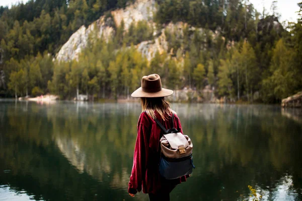 Kvinna i hatt och röd skjorta nära sjön i ett berg. — Stockfoto