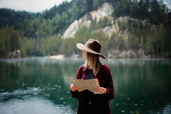 Junge Frau mit Hut und rotem Hemd mit Karte am See — Stockfoto