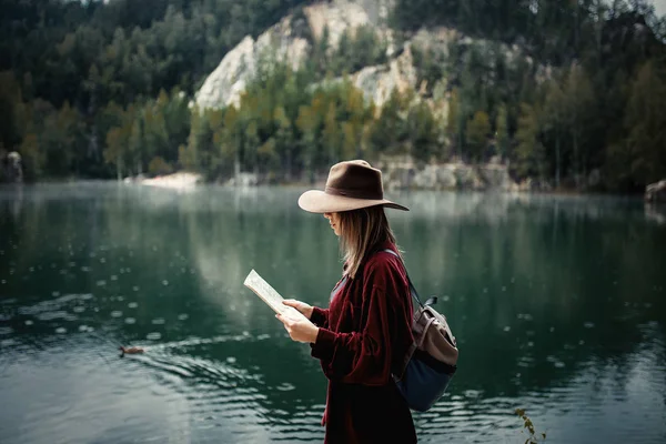Junge Frau mit Hut und rotem Hemd mit Karte am See — Stockfoto