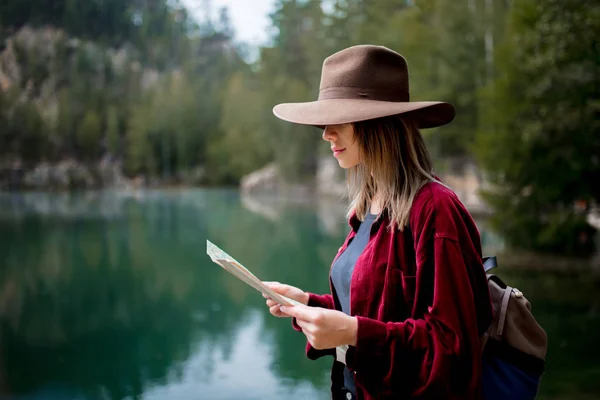 年轻女子在帽子和红色衬衫与地图附近的湖 — 图库照片
