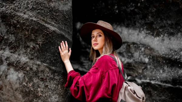 Donna in cappello e camicia rossa vicino a pietre in una montagna — Foto Stock