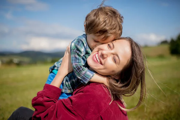 Mãe se divertir com um filho em um prado nas montanhas — Fotografia de Stock