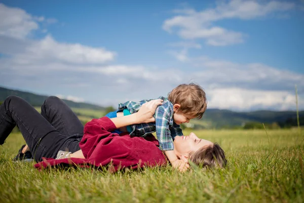 Madre tener una diversión con un hijo en un prado en las montañas — Foto de Stock