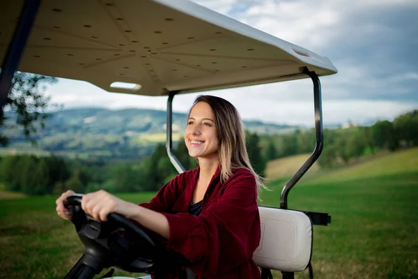 Young woman have a fun with golf buggy car on a field in mountains — Stock Photo, Image